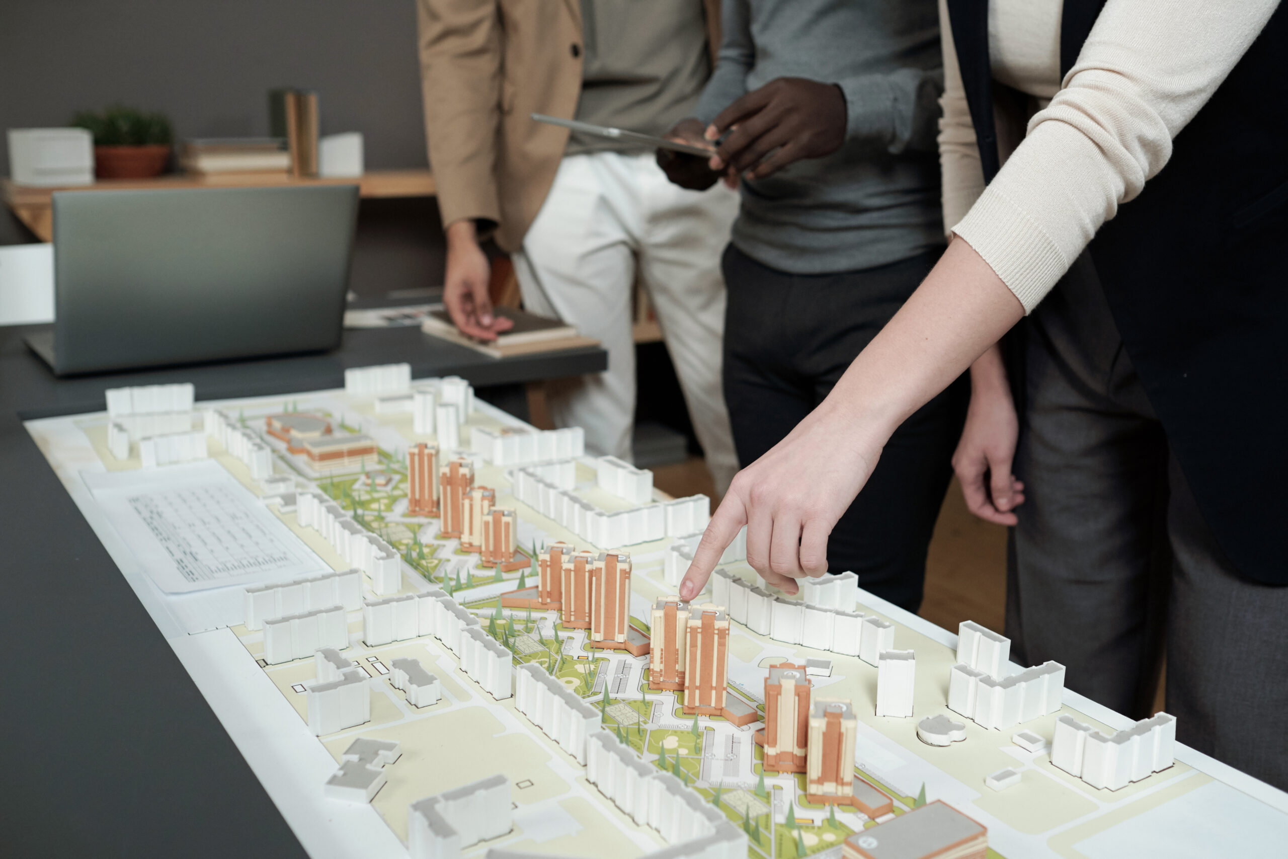 Hand of female architect pointing at layout during presentation of commercial development and explaining how to navigate development assessment rules